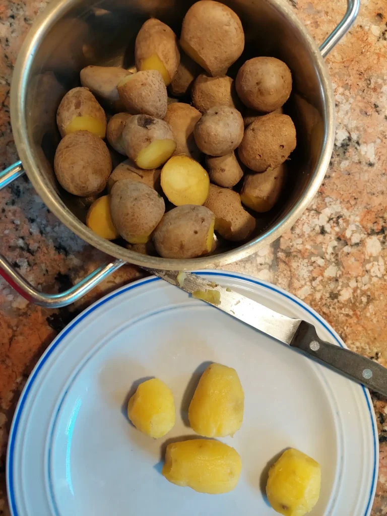 Gekochte Kartoffeln schälen und halbieren